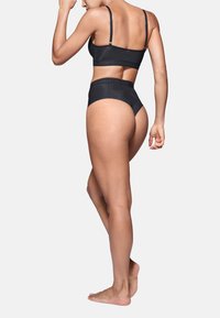 Set di reggiseno nero senza cuciture e culotte a vita alta, caratterizzato da una texture liscia e un sottile logo del brand sui nastri elastici.