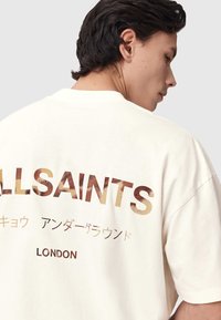 Κρεμ υπερμεγέθη μπλουζάκι με γραφικό στο πίσω μέρος που αναγράφει "ALLSAINTS" με υφασμένο, βαθμιαίο γράμμα και επιπλέον κείμενο στα ιαπωνικά και "LONDON".