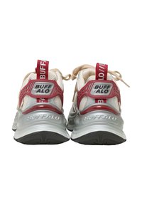Een paar witte en rode Buffalo merk sneakers gezien van achteren, met dikke zolen en gebrande hiel-lussen.