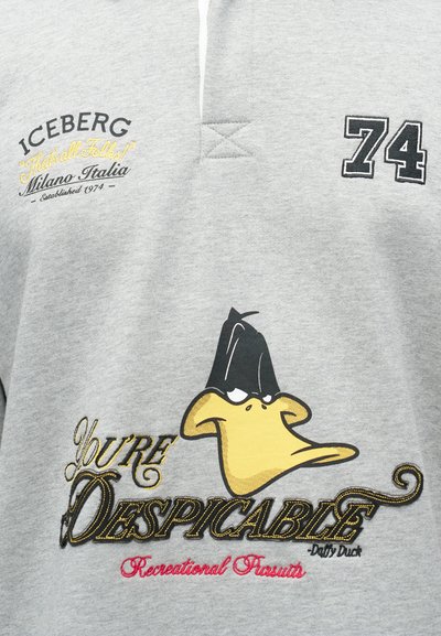 Γκρι πόλο μπλούζα με μαύρο και κίτρινο κεντημένο κείμενο "Είσαι Απαίσιος" και σχέδιο ενός καρτούν πάπιας με καπέλο. Η μάρκα "Iceberg" είναι ορατή.