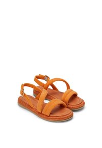 Sandales en daim orange avec deux bandes avant larges et une sangle de cheville réglable. La semelle légère présente une texture tressée sur le bord.