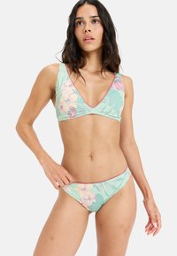 Bloemen bikini set in lichtgroen met roze accenten. De top heeft een V-hals ontwerp; de onderkant is van het low-rise type. Het materiaal lijkt glad en rekbaar.
