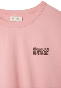 Lyserød bomulds T-shirt med rund halsudskæring, der har "AMERICAN VINTAGE" i fed sort skrift på forsiden. Blød tekstur, afslappet design.