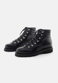 Botas de senderismo de cuero negro con puntera redondeada, cuello acolchado, ganchos de metal para los cordones y suela de goma gruesa, con una textura suave y un diseño robusto.