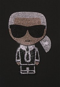 Svart tyg med en strassdesign av en karaktär i solglasögon, som bär en kostym med slips, med en monokrom färgskala.