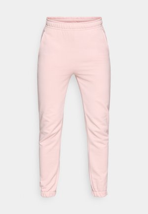 Pantalons de survêtement roses clairs en tissu doux, dotés d'une taille élastique, de jambes tapered et de poignets élastiques aux chevilles. Deux poches latérales.