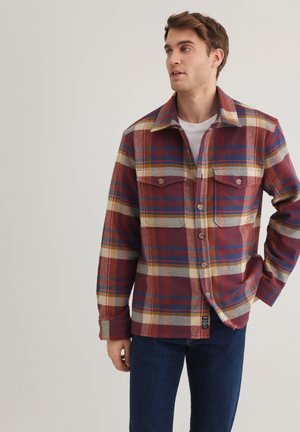 Plaid shirt featuring red, blue, and yellow colors, made of woven fabric, with two chest pockets and button front closure.