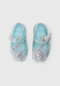 Sapatilhas de gel transparente azul com detalhes em prata, apresentando um laço e um enfeite decorativo em forma de floco de neve. O design interior mostra um personagem.