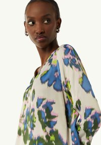 Bluse mit floralem Muster in lebendigen Blau-, Grün- und Pinktönen. Aus leichtem Stoff gefertigt, mit einem V-Ausschnitt und langen Ärmeln.