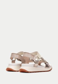 Paksut sandaalit, joissa on kudotut metalliset nauhat, beigen ja kermanvärinen yläosa, säädettävä takanauha ja kumipohja, jossa on teksturoitu kulutuspinta.