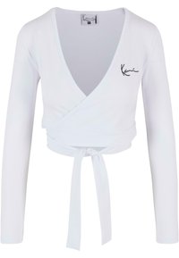 Biely dlhý rukáv crop top s prekrývajúcim dizajnom, hlbokým V-výstrihom a viazaním v páse. Obsahuje vyšívané akcenty. Hladká textura.