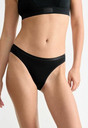 Schwarze Tanga-Unterwäsche mit glatter Oberfläche, ausgestattet mit einem breiten Bund und minimalistischem Design für diskreten Tragekomfort. weiches Stoffgefühl.