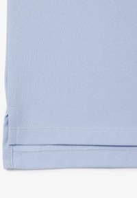 Tissu bleu clair plié soigneusement avec un tissage texturé visible et une couture d'ourlet sur un fond blanc propre.