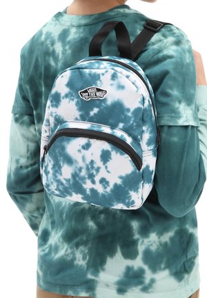 Personne portant un petit sac à dos Vans tie-dye bleu et blanc avec des fermetures éclair et des bretelles noires, sur une chemise à manches longues tie-dye assortie.