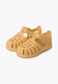 Gelbe Gummisandalen mit offenem Design, die einen Riemen über den oberen Bereich und mehrere Aussparungen für Atmungsaktivität aufweisen.