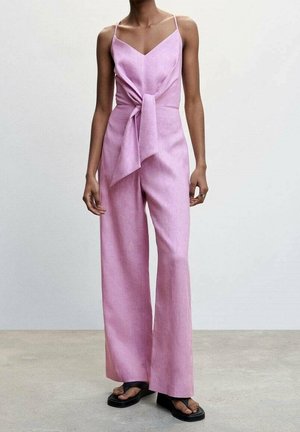 Roze linnen jumpsuit met een V-hals, dunne bandjes en een gestrikte taille. Losse, wijde pijpen, gecombineerd met platte zwarte sandalen.