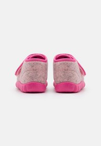 Zapatos de lona de color rosa para niños, con parte superior de tela suave y suelas de goma texturizadas, vistos desde la parte trasera sobre un fondo blanco.