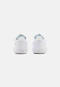 Baskets blanches avec une tige synthétique lisse, fermeture à bande Velcro, col rembourré et semelle en caoutchouc. Présente le logo "Converse All Star" sur le talon.