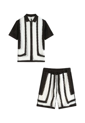 Chemise en crochet noire et blanche à manches courtes, boutonnée, avec un short assorti à taille élastique présentant des motifs géométriques rayés.