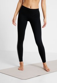 Svarta leggings med en tight passform, elastisk midja och subtila sidodetaljer. Slät yta, lämpliga för träning eller avslappnad klädsel.