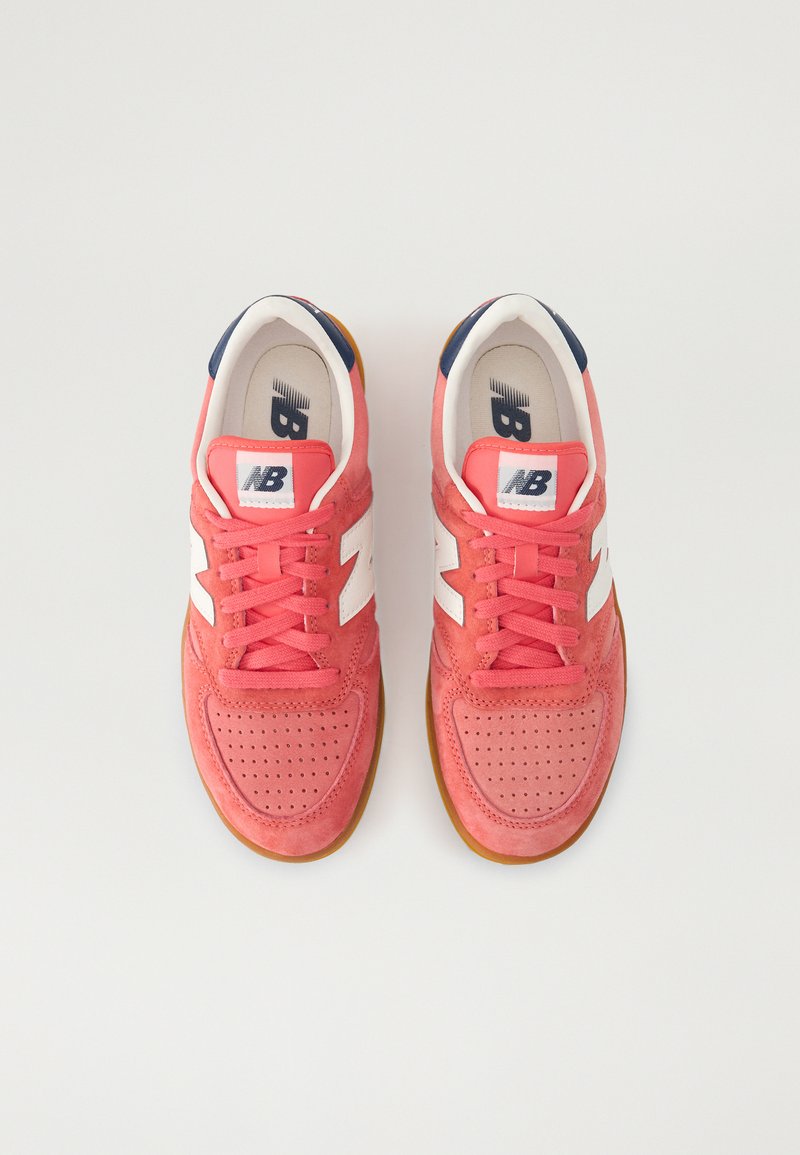 Zapatillas de ante rojo con acentos blancos, caja de puntera perforada y suela de goma texturizada. Presentan una lengüeta acolchada y una pestaña en el talón en color navy.