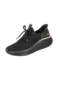 Zapatilla deportiva de malla negra con una suela gruesa negra, que presenta un acento en oro rosa y cordones planos para un ajuste seguro y un diseño transpirable.