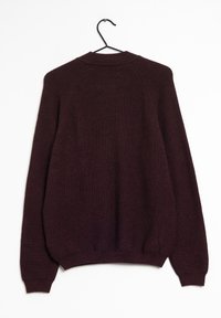 Pull en maille bordeaux avec un col rond, des manches raglan et des poignets et un ourlet côtelés. Suspendu à un crochet noir sur un fond blanc.