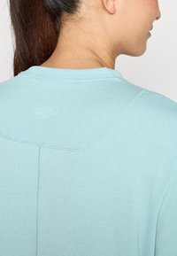 Lyseblå Nike t-skjorte med rund hals, som har subtile sydetaljer og en liten, lyseblå logo bak.