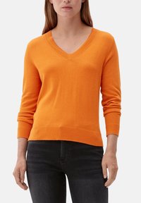 V-ringad orange tröja med långa ärmar, ribbade manschetter och nederkant, tillverkad av ett mjukt stickat material, figurnära passform och slät yta.