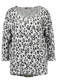 T-shirt ample gris avec imprimé léopard noir, présentant un col large et des manches trois-quarts. Tissu doux et texturé.