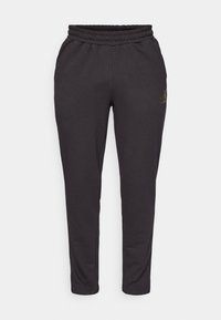 Svarta sweatpants med elastisk midja, avsmalnande ben och en diskret gul logodetalj på sidan. Tillverkade av mjukt, stretchigt material.