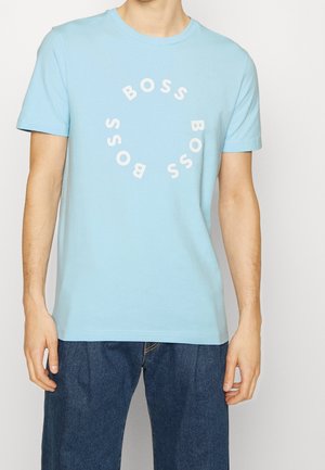 Vaaleansininen puuvillainen T-paita pyöreällä pääntiellä, jossa toistuva ”BOSS”-logo valkoisessa ympyräkuviossa rinnan kohdalla.
