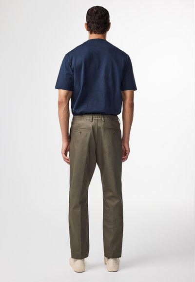 Een marineblauw overhemd met korte mouwen voor heren, gecombineerd met olijfgroene broek, met een rechte pasvorm en achterzakken met knoopsluitingen.