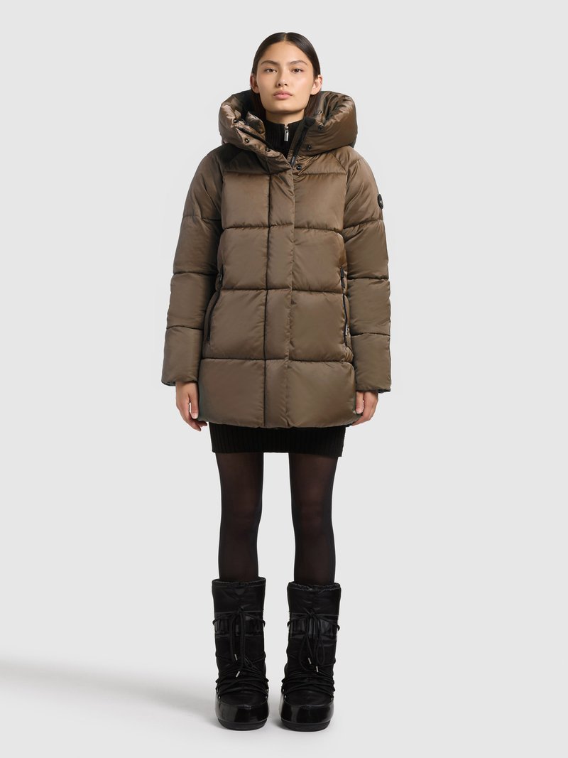 Fyldig, brun dunjakke med stor hætte, lynlås og quiltet design. Kombineret med sorte teksturerede knæhøje støvler.