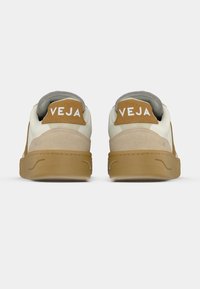 Sneakers con tomaia in pelle color crema, dettagli color cuoio e suola in gomma strutturata. Presentano il logo distintivo "VEJA" sul tallone.