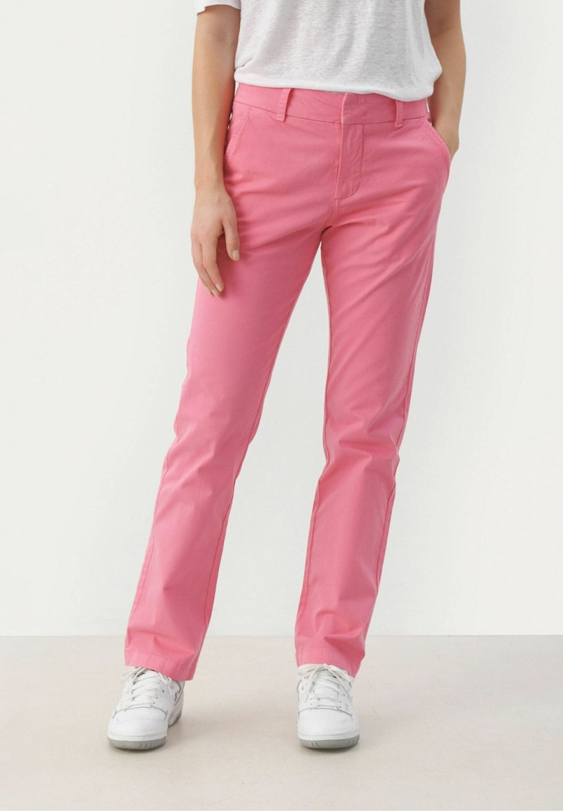 Rosa byxor i rak ben-design, tillverkade av bomullsblandat material. Har framfickor och ett enkelt midjeband. Tillsammans med vita sneakers.