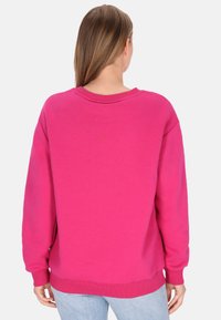 Fukszia pulóver kerek nyakkivágással, ejtett vállakkal és bordázott mandzsettákkal. Puha, sima tapintású anyagból készült, egyszínű kivitelben.