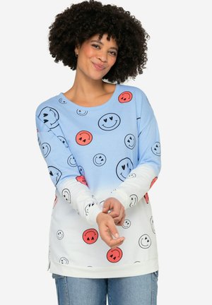 Langärmliger Sweatshirt in Hellblau und Weiß, mit einem Smiley-Gesicht-Muster in Schwarz und Rot. Weicher Stoff, lockere Passform, seitliche Schlitze.