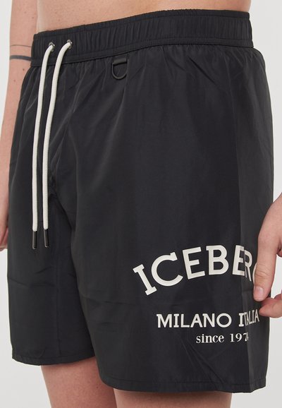Pantaloncini da bagno neri in tessuto liscio, con stampa del logo bianco sulla gamba sinistra e vita elastica con coulisse per la regolazione.