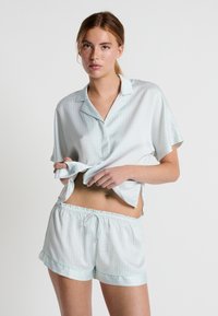 Ensemble de pyjama à manches courtes en vert menthe clair avec un motif à carreaux. Le haut présente un col à cran et le short dispose d'une taille élastique.