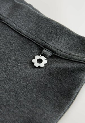 Grijze stof met een gladde textuur, voorzien van een witte bloemenaccent met een centraal gat dat aan de tailleband is bevestigd.