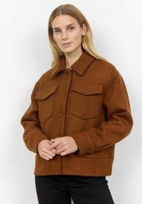 Veste en polaire marron avec un col, deux poches avant et fermeture à boutons. Matériau texturé avec une coupe décontractée.