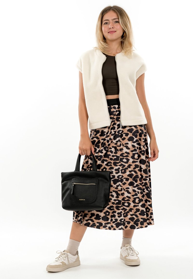 Kreemjas fliisvest, pruun lühike top, lehmakujundusega seelik, must tekstuurne käekott ja valged tossud beežide detailidega.