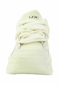 Sneaker z jasnożółtą, gładką cholewką, z perforacjami, okrągłym czubkiem, grubymi sznurowadłami i masywną, teksturowaną podeszwą.