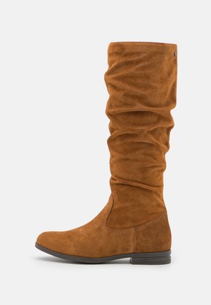 Botte haute en daim marron jusqu'au genou avec tige froissée, talon plat et bout arrondi, présentée de profil sur un fond blanc.