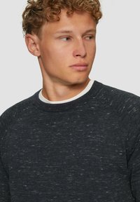 Donkergrijze gebreide trui met ronde halslijn en witte binnenkraag, voorzien van een breipatroon en een relaxte pasvorm.