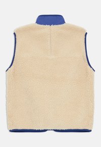 Gilet di pile beige con colletto alto, aperture per le braccia blu e tessuto testurizzato. Presenta una cucitura sul retro e nessuna chiusura visibile nella parte frontale.