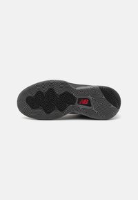 Sort gummisål til sneakers med teksturerede bølgemønstre og et rødt logo. Cirkulære og sekskantede detaljer forbedrer greb og holdbarhed.