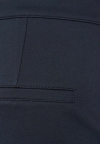 Tissu bleu foncé avec un tissage texturé, comportant une couture horizontale et un petit détail de poche rectangulaire à l'arrière.