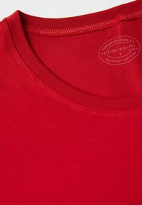 Czerwona bawełniana koszulka T-shirt z okrągłym dekoltem, gładką fakturą i przeszyciami. Posiada nadrukowaną metkę wskazującą na wysoką jakość.